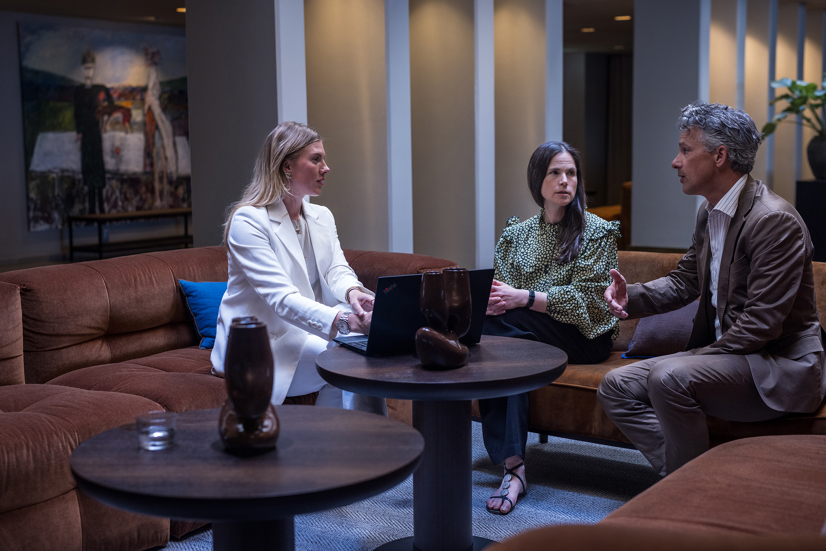 Två kvinnor och en man sitter i ett möte